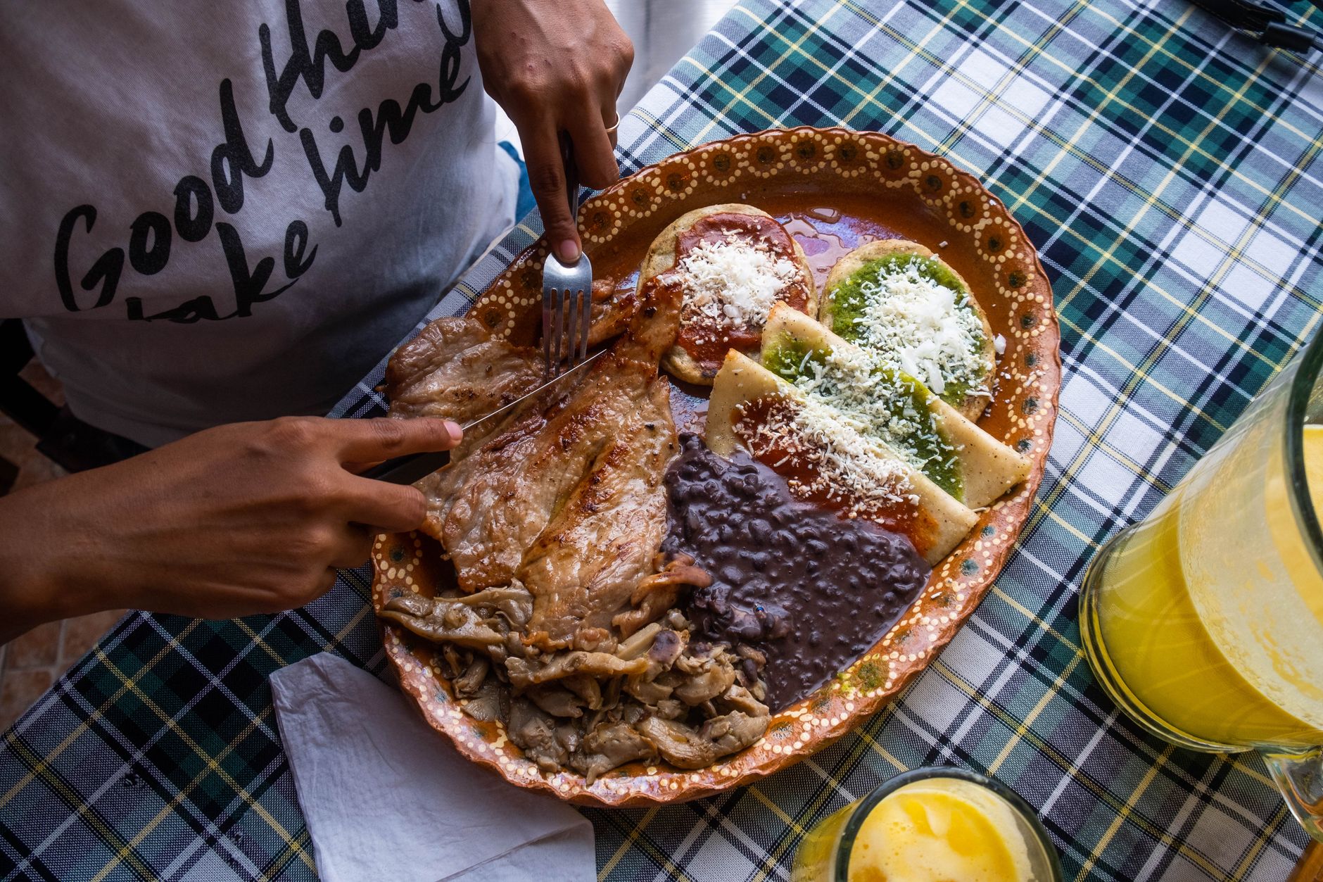 A plate of enchiladas verdes and mole-style enchiladas with beans and grilled meat.