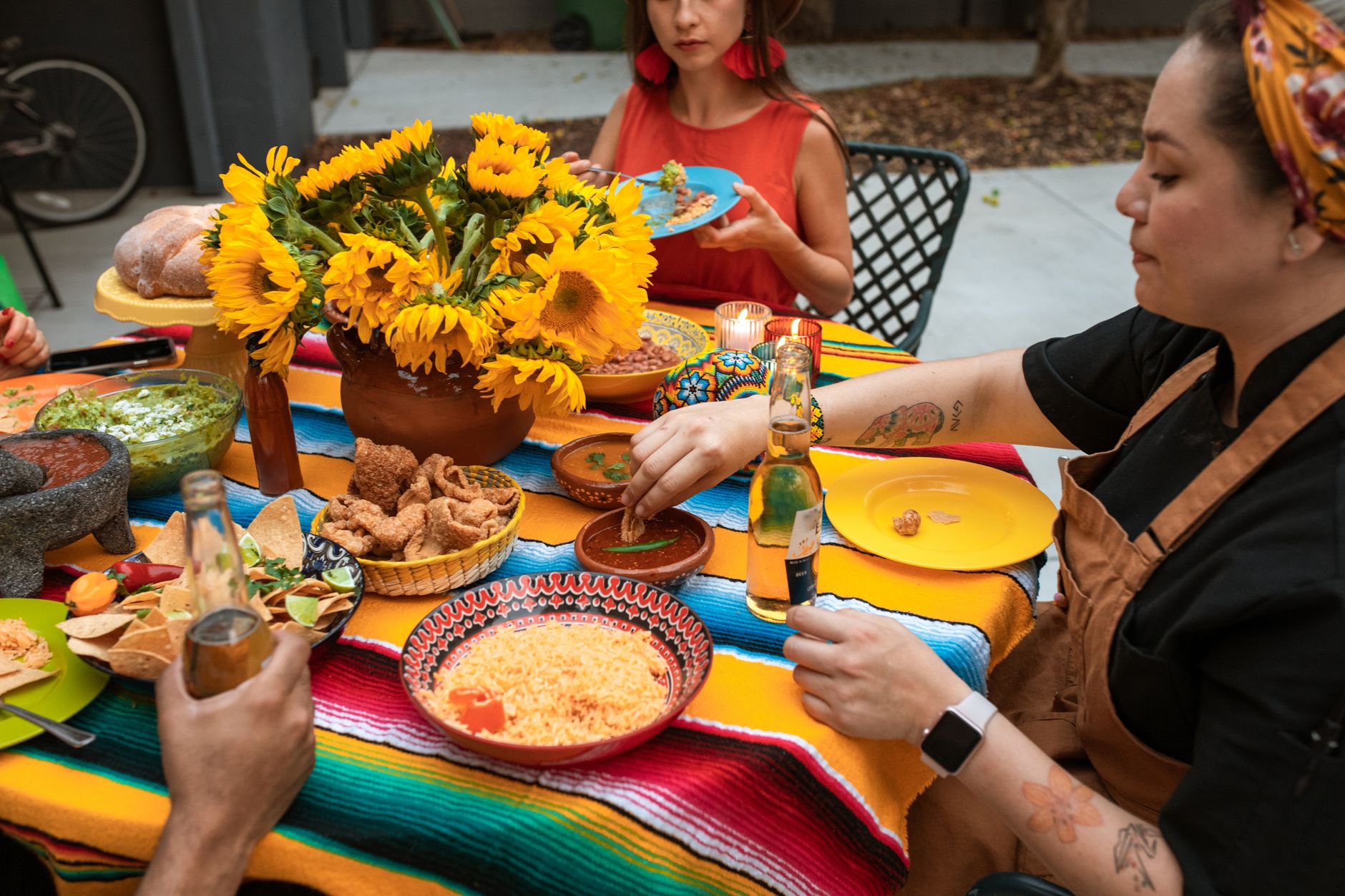 A table spread with rice, beans, guacamole, chicharron and salsas, shared family-style.