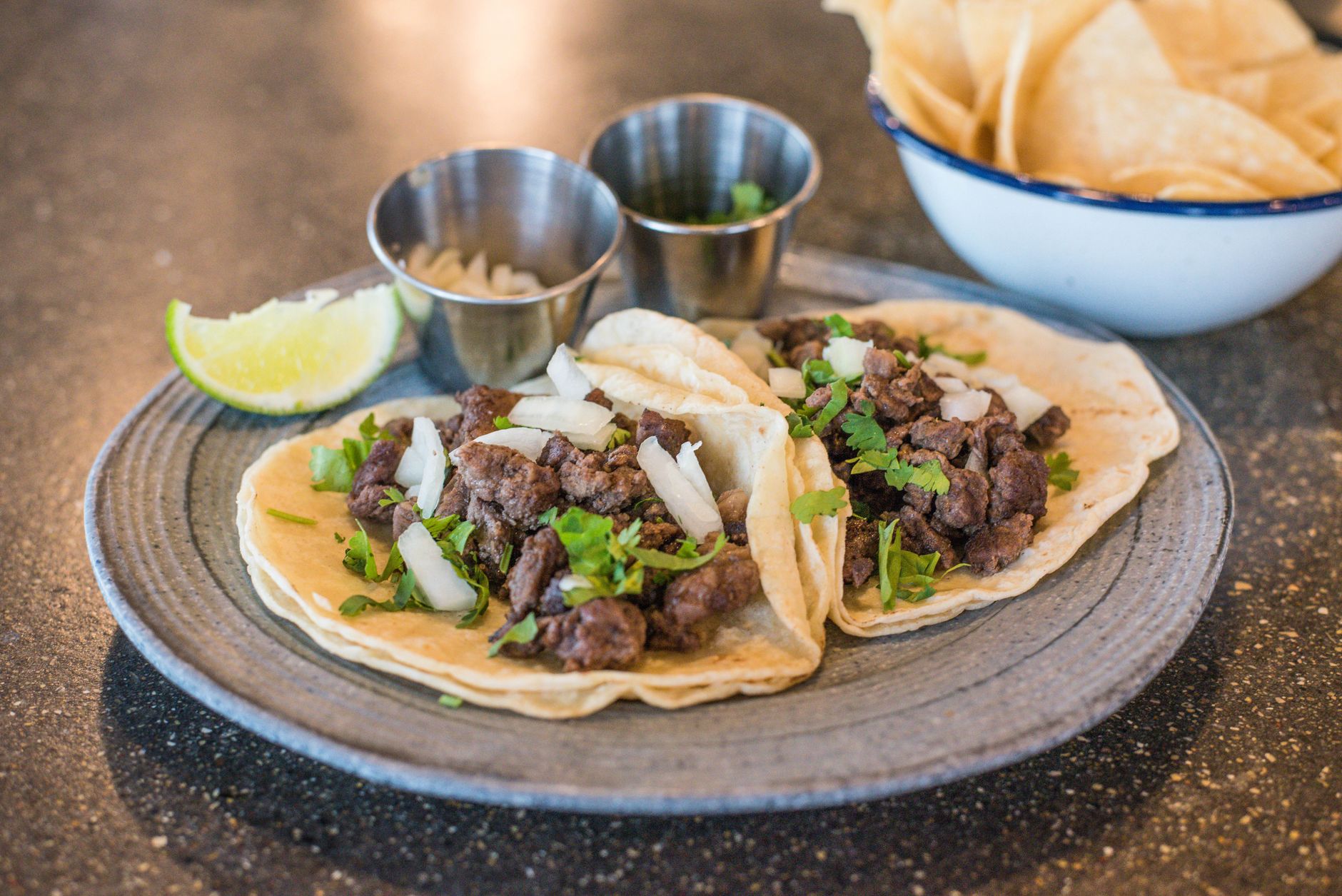 Bistec street tacos with lime, onion and cilantro, served taqueria-style with chips and salsa.