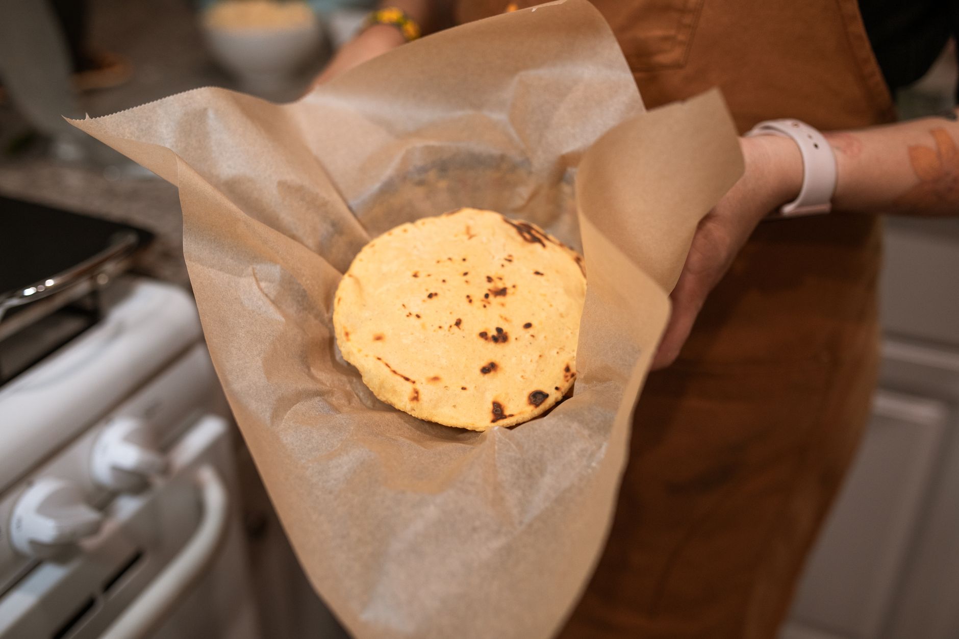 A fresh corn tortilla, hot off the comal, wrapped in paper.